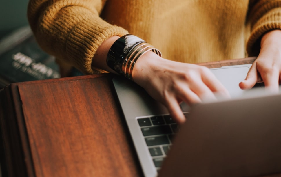 person's hands typing on a laptop