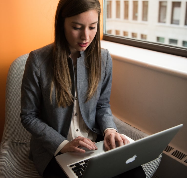 woman in suit jacked typing on a computer